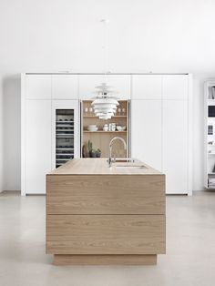 a kitchen with white cabinets and an island in the middle is lit by a pendant light