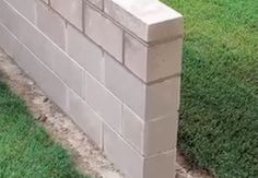 a man is working on a brick wall in the yard with concrete blocks laid around it