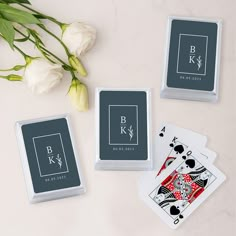 four playing cards with the letter b and k on them next to a bouquet of flowers