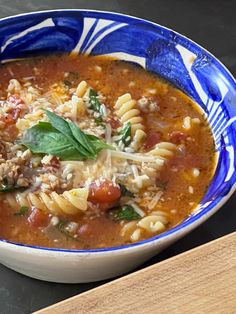 a blue and white bowl filled with pasta soup