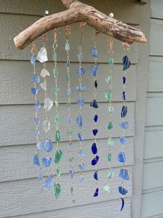 a wind chime hanging from a tree branch with blue and green glass beads on it