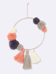 the multi - colored tasselled hoop is hanging on a white wall