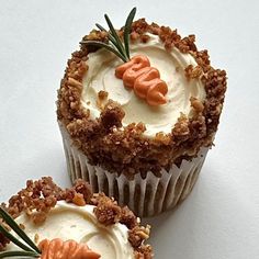 two cupcakes with white frosting and orange decorations