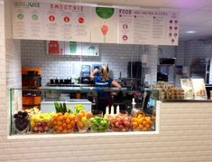 a woman standing behind a counter filled with lots of fruit