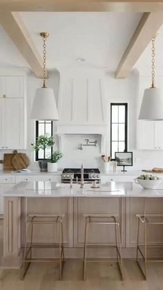 a large kitchen with white cabinets and wooden beams on the ceiling, along with two stools