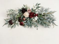 an arrangement of flowers and greenery on a white background