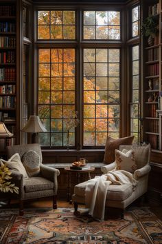 a living room filled with furniture and a large window covered in fall leaves next to a book shelf