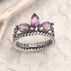 Rosalia Tarigan of Indonesia wows us with this stunning cocktail ring fit for a queen. Crafted from sterling silver, the ring features three purple amethysts that come together in a cluster to form a fabulous crown. Queen Of The Jungle, Amethyst Cocktail Ring, Purple Crown, Ring Fit, Cocktail Ring, Purple Amethyst, Cocktail Rings, Gemstone Rings, Jewelry Rings