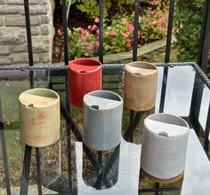 four different colored vases sitting on top of a glass table