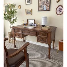 a wooden desk sitting in front of a wall with pictures on it and a potted plant