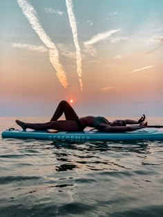 a woman laying on top of a surfboard in the ocean