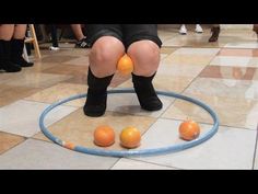 a woman sitting on top of a hula hoop surrounded by oranges