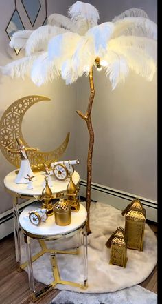 a white table topped with lots of gold and white items next to a lamp on top of a wooden floor