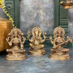 three brass figurines sitting next to each other on top of a cement floor