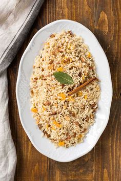 a white plate topped with rice next to a cup of tea and a wooden spoon