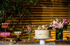 an assortment of desserts and pastries displayed on a table with flowers in vases