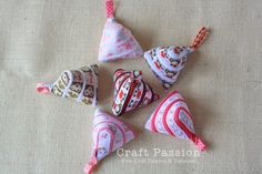 five small ceramic ornaments are arranged on a cloth surface, one is pink and the other is white