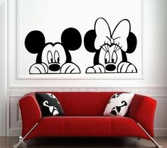 a living room with a red couch and mickey mouse wall decal