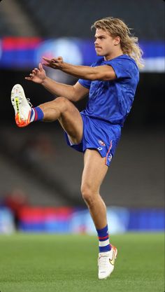 a young man kicking a soccer ball on top of a field with his foot in the air