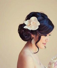 a woman in a wedding dress holding a bouquet with white flowers on it's head