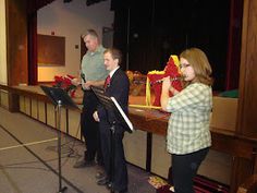 three people standing in front of microphones with music sheets on the table behind them