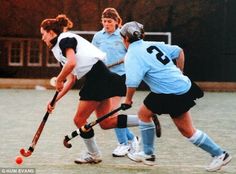 two girls playing field hockey on an asphalt court with the ball in front of them