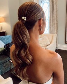 a woman with long hair wearing a white dress and flower in her hair, looking out the window