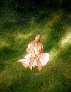 a woman sitting in the grass with her hands on her knees