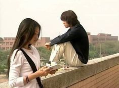 two people sitting on a ledge looking at something