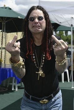 a man with dreadlocks making the peace sign while standing in front of a tent