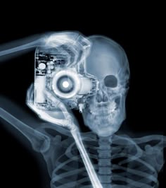 an x - ray skeleton holding a camera in it's right hand and looking at the screen