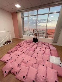 a person sitting on top of a bed made out of pink sheets with black hearts