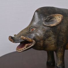 a wooden sculpture of a boar with its mouth open and tongue out on a table