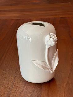 a white vase sitting on top of a wooden table