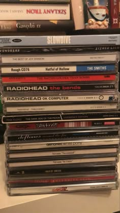 a stack of cd's sitting on top of a white table next to a pile of books