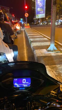 a motorcycle parked on the side of a street at night with traffic lights in the background