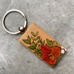 a wooden keychain with flowers painted on it sitting on a marble counter top