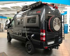 a black van is parked in a showroom with other vehicles and equipment on display