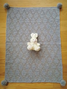 a white teddy bear sitting on top of a blue rug