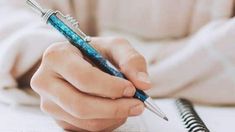 a person holding a pen and writing on paper