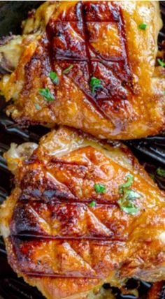 two pieces of cooked chicken sitting on top of a black grill grate with parsley