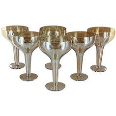 six champagne goblets with gold rims are lined up on a white background