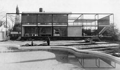 an old black and white photo of a man standing in front of a swimming pool