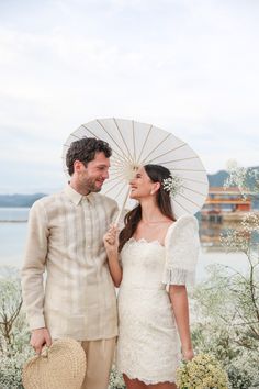 a man and woman standing next to each other holding an umbrella