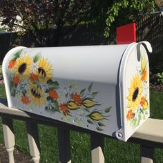 a painted mailbox sitting on the side of a fence