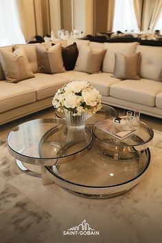 a living room filled with furniture and flowers on top of a glass table in front of a couch