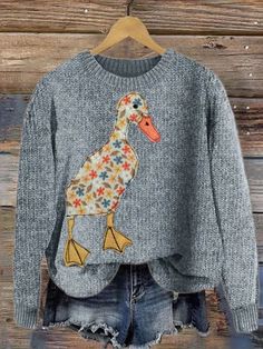 a sweater with a bird on it hanging from a wooden wall