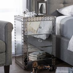 a mirrored nightstand with silver studded drawers and shoes on the floor next to it