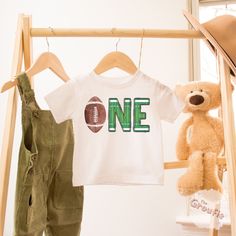 Celebrate your little one's 1st birthday with this 1st year down shirt. And dress up the whole family with these matching football birthday outfits! SHIRT DETAILS * Bella+Canvas - Adult, Youth, and Toddler shirts * Rabbit Skins - Baby shirts and bodysuits * Next Level - Women's tank tops * Gildan - alternative option if the primary brand is out of stock * 100% soft cotton SIZING * Our shirts are unisex - Run true to size and have a relaxed fit. Order one size smaller for a further slim fit. * If you are unsure about what size to order, please refer to the size chart in the photos or reach out to us. * To measure, lay your favorite shirt flat. Measure armpit to armpit and the length, then compare to the size chart in the photos. * Incorrect size can not be refunded or exchanged. DIRECT TO G 1st Year Down Birthday Shirt, 1st Birthday Football Family Shirts, Customizable Family Matching T-shirt For First Birthday, Green Graphic Print T-shirt For First Birthday, Cute First Birthday T-shirt With Custom Print, Family Shirts Matching, Football Birthday, 1st Birthday Outfits, Baby Shirts