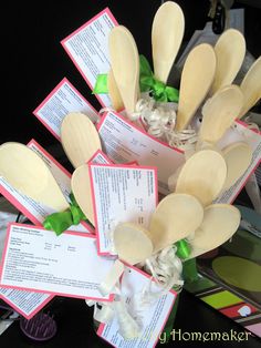 several wooden spoons are arranged in a bouquet with green ribbons and tags on them